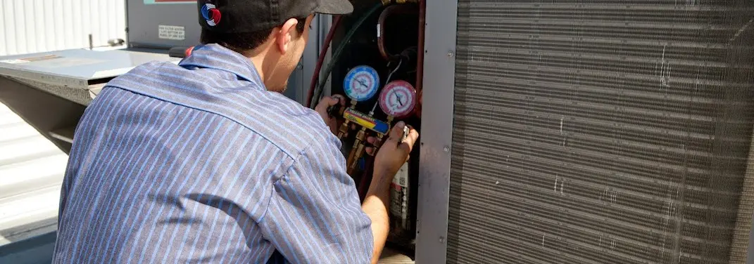 HVAC technician servicing a condenser unit in Milton